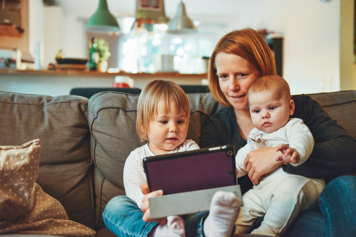 Mom relaxing on the couch at home with her two little ones