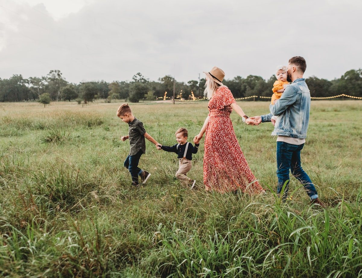 Young family walking hand in hand through a green field